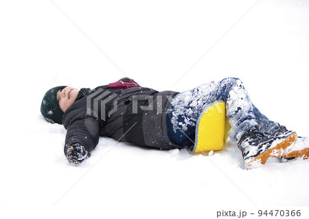 Child in winter. The boy fell on the sled and lies in the snow. 94470366
