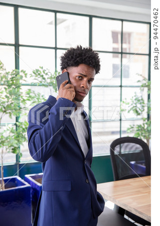 Serious employee talking on phone and looking at camera Serious employee talking on phone and looking at camera 94470462
