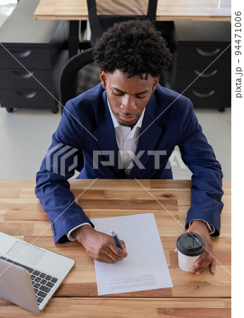 Concentrated man sitting at desk and signing contract 94471006