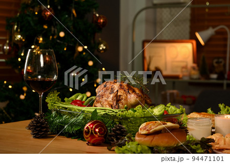 Thanksgiving table with roasted turkey, red wine and sides dishes in decorated room with a Christmas tree Thanksgiving table with roasted turkey, red wine and sides dishes in decorated room with a Christmas tree 94471101