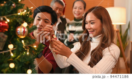 Loving young couple decorating Christmas tree with baubles. Celebration, holidays and Christmas concept 94471186