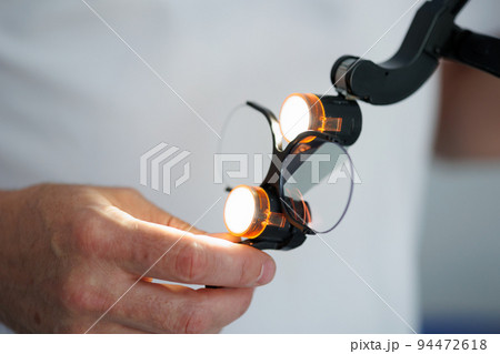 Close up view of dentist hands with glasses with surgical binocular loupes 94472618