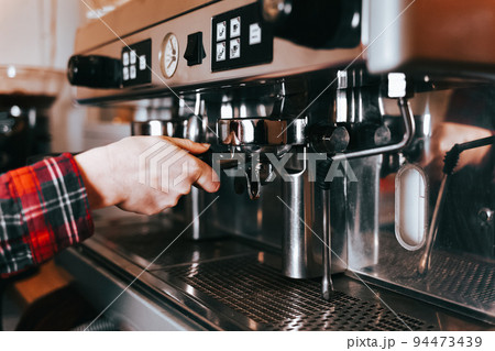 Barista makes aromatic coffee. Process of making latte coffee on a coffee machine in a cafe.. Barista makes aromatic coffee. Process of making latte coffee on a coffee machine in a cafe.. 94473439