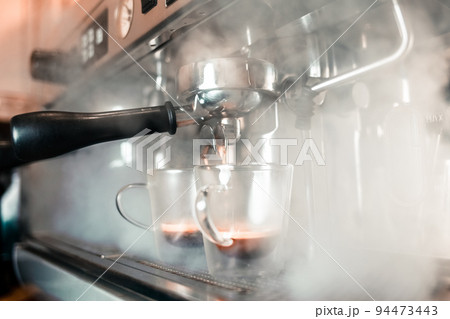 Fragrant espresso flows from a coffee machine into a cup. Making aromatic coffee with professional coffee equipment.. 94473443
