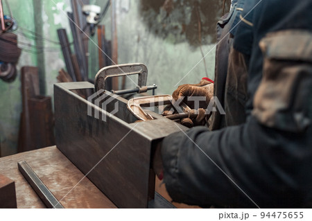 Man clamps iron products into c-clamps. Man works with clamps. Steel workshop concept. 94475655