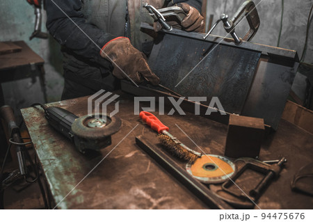 Man clamps iron products into c-clamps. Man works with clamps. Steel workshop concept 94475676