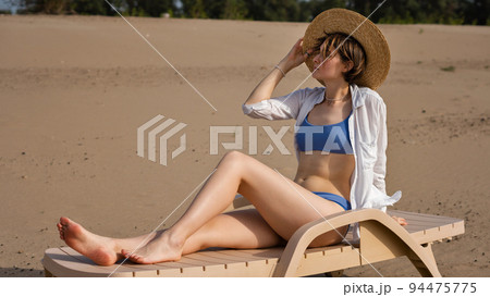 Girl on beach sunbathing sitting on sun lounger 94475775