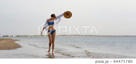 Girl in bikini walks on beach 94475780