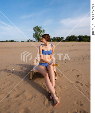 Girl on beach sunbathing sitting on sun lounger Girl on beach sunbathing sitting on sun lounger 94475794