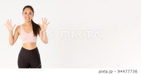 Sport, wellbeing and active lifestyle concept. Smiling strong and slim asian female fitness instructor teaching lesson, explain ten steps for perfect body and productive workout, white background Sport, wellbeing and active lifestyle concept. Smiling strong and slim asian female fitness instructor teaching lesson, explain ten steps for perfect body and productive workout, white background 94477736