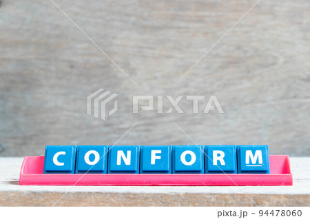 Tile alphabet letter with word conform in red color rack on wood background Tile alphabet letter with word conform in red color rack on wood background 94478060