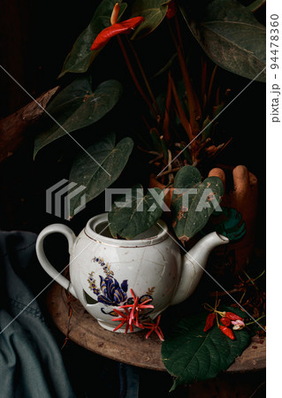 Broken vintage porcelain teapot on a coffee table shot in low light Broken vintage porcelain teapot on a coffee table shot in low light 94478360
