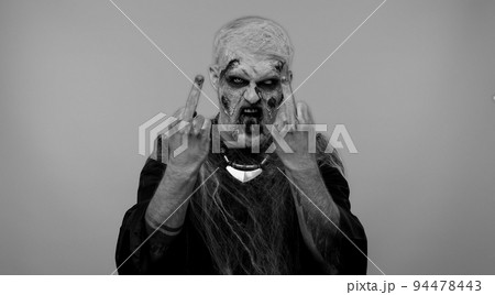 Aggressive Halloween zombie man showing around middle fingers, demonstrating protest rude gesture 94478443