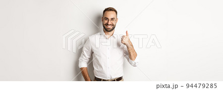 Satisfied successful boss showing thumb up, approve and praise good work, standing over white background 94479285