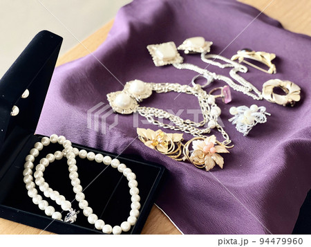 紫の布の上に置いたたくさんのジュエリーとパールのネックレス_ななめ 紫の布の上に置いたたくさんのジュエリーとパールのネックレス_ななめ 94479960