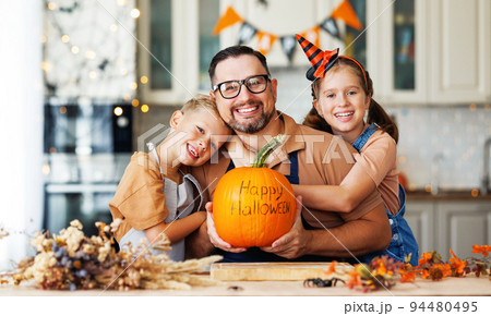 Happy family children hugging father with pumpkin with inscription Happy halloween 94480495