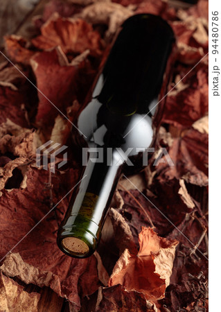 Red wine on dried-up vine leaves. 94480786