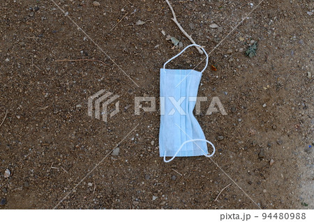 An old medical mask from covid 19 (COVID-19) is lying on the stre 94480988