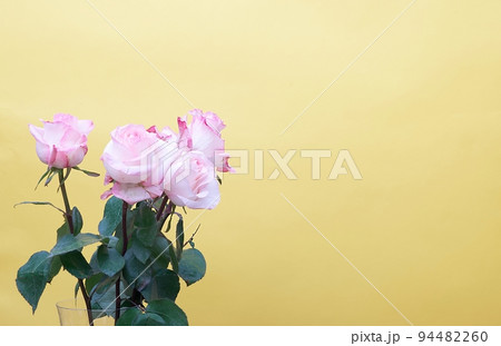 Elegant stylish small bouquet of roses in a crystal transparent vase on a yellow background in a photo studio.  94482260