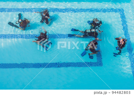 Diving instructor and students. Instructor teaches students to dive Diving instructor and students. Instructor teaches students to dive 94482803