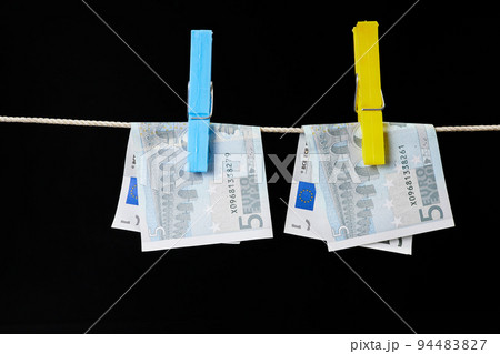 Five euro banknotes fastened with clothespins are dried on a clothesline on dark background Five euro banknotes fastened with clothespins are dried on a clothesline on dark background 94483827