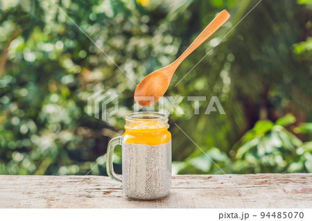 Chia seed pudding with almond milk and fresh mango topping with levitating spoon 94485070