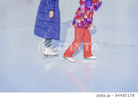 Abstract unrecognizable mother with daughter skating outdoors in skating rink. Winter activity, sport 94485159