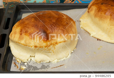Handmade home stile delicious pies with different fillings cooked in the dark warm oven are preparing on the cooking paper at kitchen using special form inside the hot oven. Close-up picture. 94486205