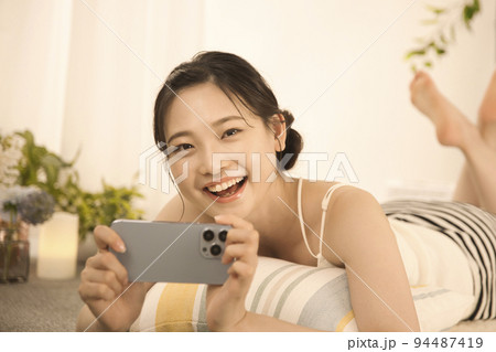 寝転んでスマホを見る若い女性 寝転んでスマホを見る若い女性 94487419