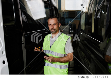 Man Inspecting Cars At Factory Man Inspecting Cars At Factory 94489531