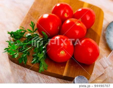 Delicious tomatoes with fresh parsley on a wooden surface 94490707
