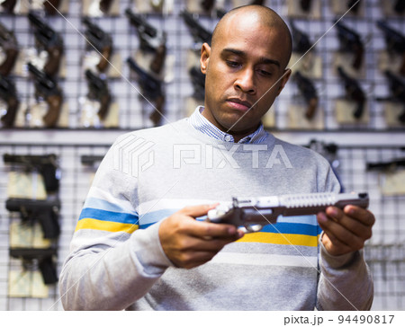 Latino choosing sporting and hunting revolvers in gunsmith shop 94490817