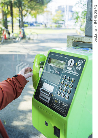 公衆電話の受話器を持つ女性の手 公衆電話の受話器を持つ女性の手 94490841