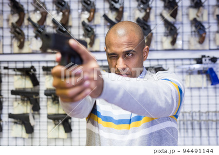 Man chooses combat pistol at gun store Man chooses combat pistol at gun store 94491144