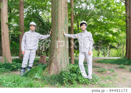 森の中に立つ　作業服を着た若い男女 94491172
