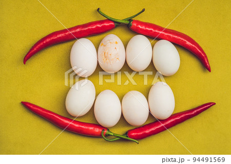 Eggs and red pepper in the form of a mouth with teeth. One of the teeth is sick in the form of a cracked egg. Sick tooth concept Eggs and red pepper in the form of a mouth with teeth. One of the teeth is sick in the form of a cracked egg. Sick tooth concept 94491569