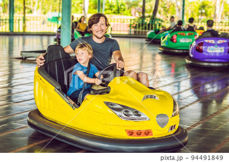 Father and son having a ride in the bumper car at the amusement park 94491849