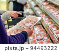 スーパーで肉を選ぶ夫婦の手元 94493222