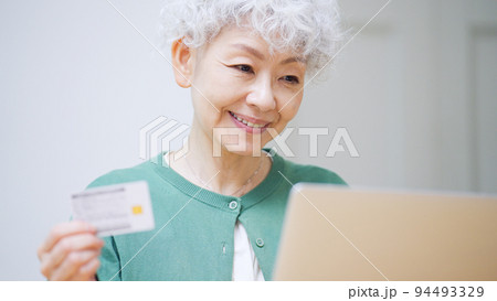 カードを見てパソコンに入力するシニア女性 94493329