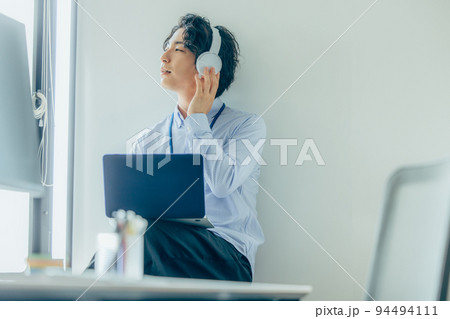 オフィスで働くカジュアル衣装の若い男性 オフィスで働くカジュアル衣装の若い男性 94494111