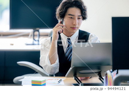 オフィスでスマホで電話する若いビジネスマン 94494121