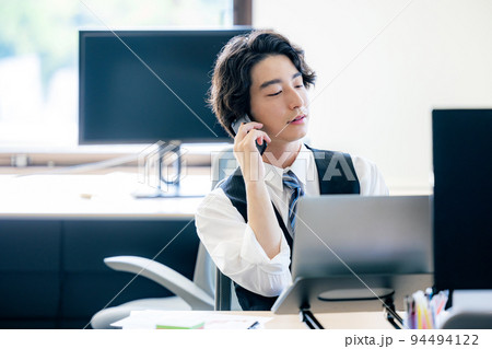 オフィスでスマホで電話する若いビジネスマン 94494122