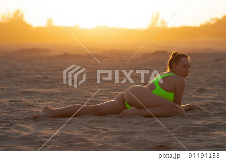 Seductive model in swimsuit kneeling on sandy beach Seductive model in swimsuit kneeling on sandy beach 94494133