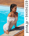 Alluring lady leaning on pool edge and looking away 94494159