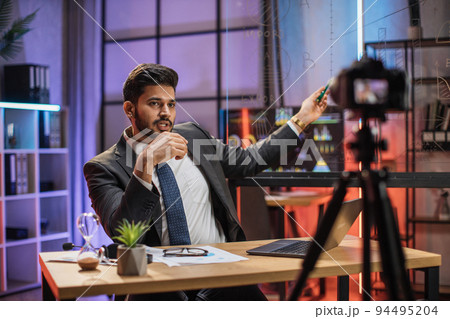 Attractive confident arab skilled bearded businessman explaining online economic charts Attractive confident arab skilled bearded businessman explaining online economic charts 94495204