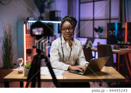 Confident african american businesswoman, broker in white shirt sitting in front of camera Confident african american businesswoman, broker in white shirt sitting in front of camera 94495245