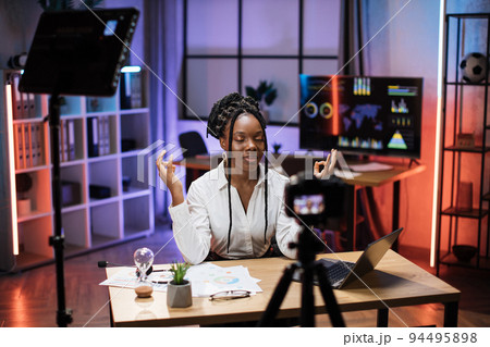 Relaxed african businesswoman in formal wear meditating with closed eyes and mudra hands 94495898