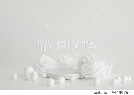 White marble podium on the white background with pearls and flowers. Podium for product, cosmetic presentation. Creative mock up. Pedestal or platform for beauty products. 94499762