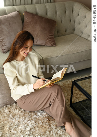 Pleasant young woman resting in cozy home and writing her diary. Leisure activity, positive mood concept Pleasant young woman resting in cozy home and writing her diary. Leisure activity, positive mood concept 94499939