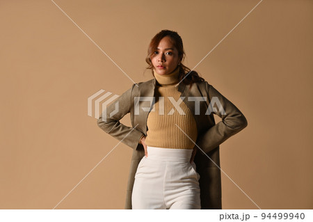 Beautiful fashionable woman in autumn outfit posing on beige background. Fashion studio photo, Autumn fashion and beauty concept Beautiful fashionable woman in autumn outfit posing on beige background. Fashion studio photo, Autumn fashion and beauty concept 94499940
